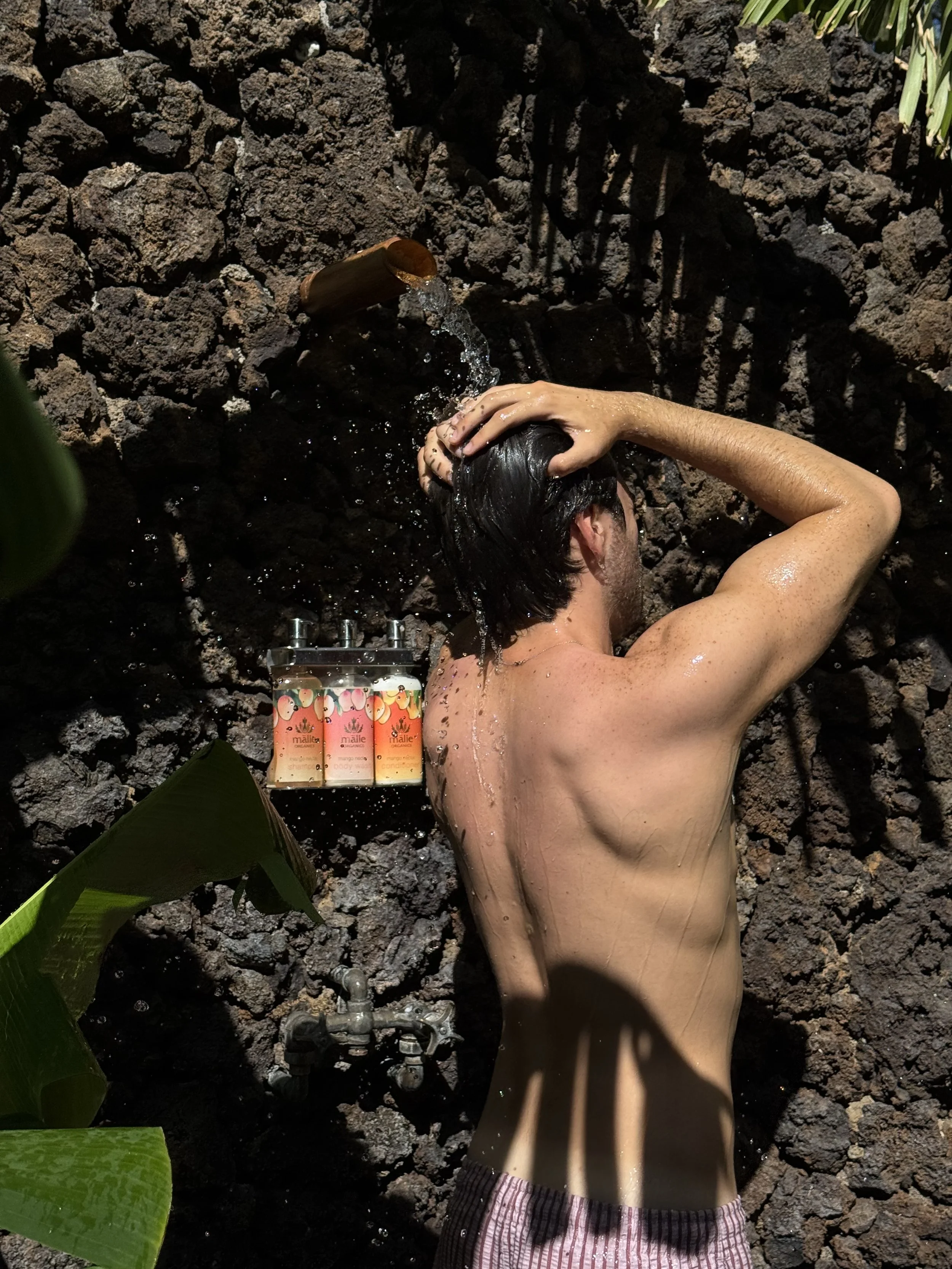 Guest showering outdoors against the natural rock wall